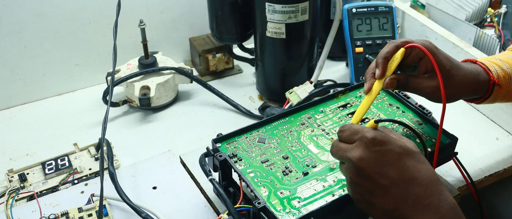 Teknisi mengukur papan sirkuit AC menggunakan multimeter.
