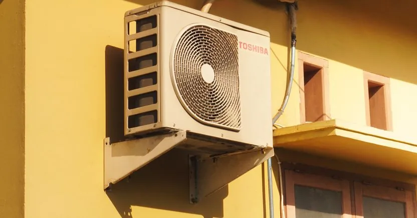 Unit outdoor AC terpasang pada dinding bangunan.